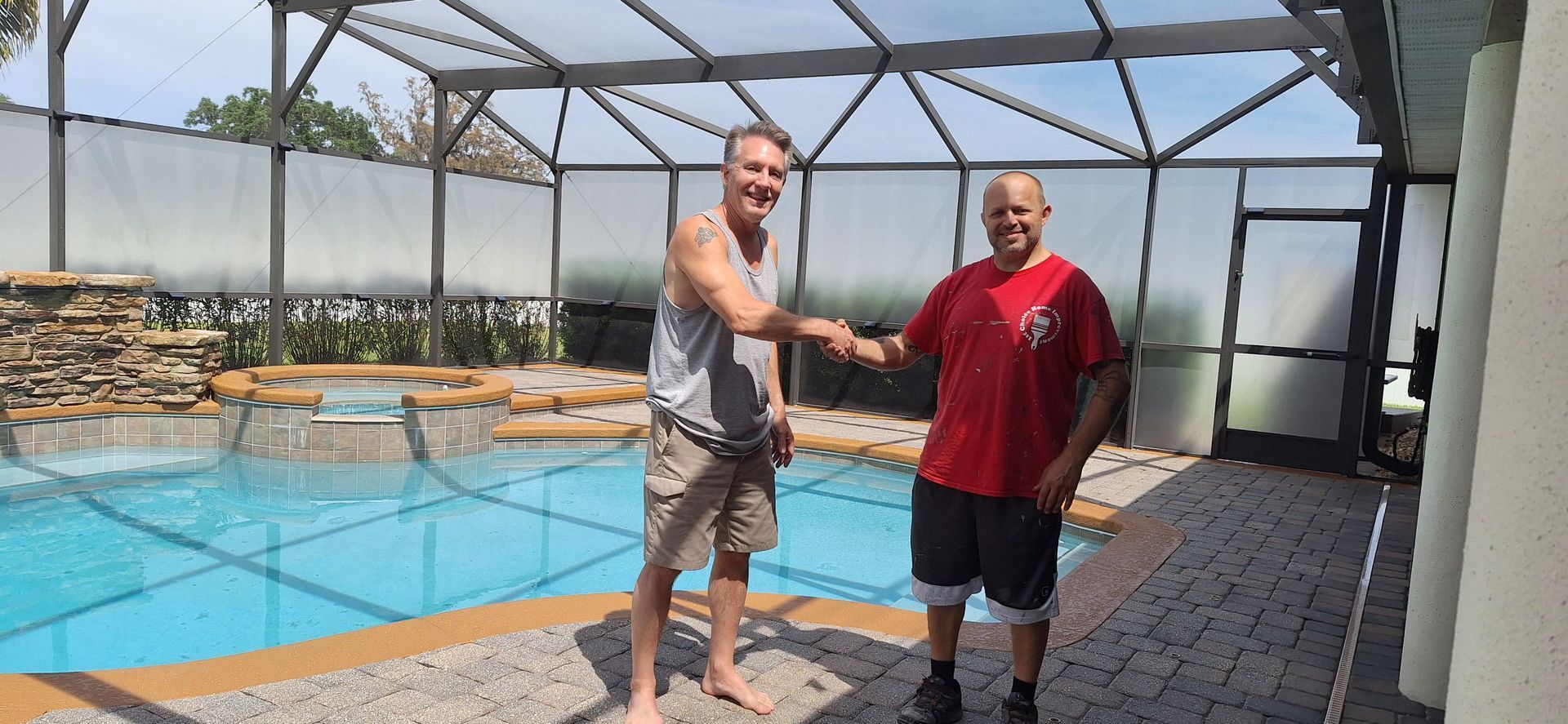 Two men are shaking hands in front of a swimming pool.