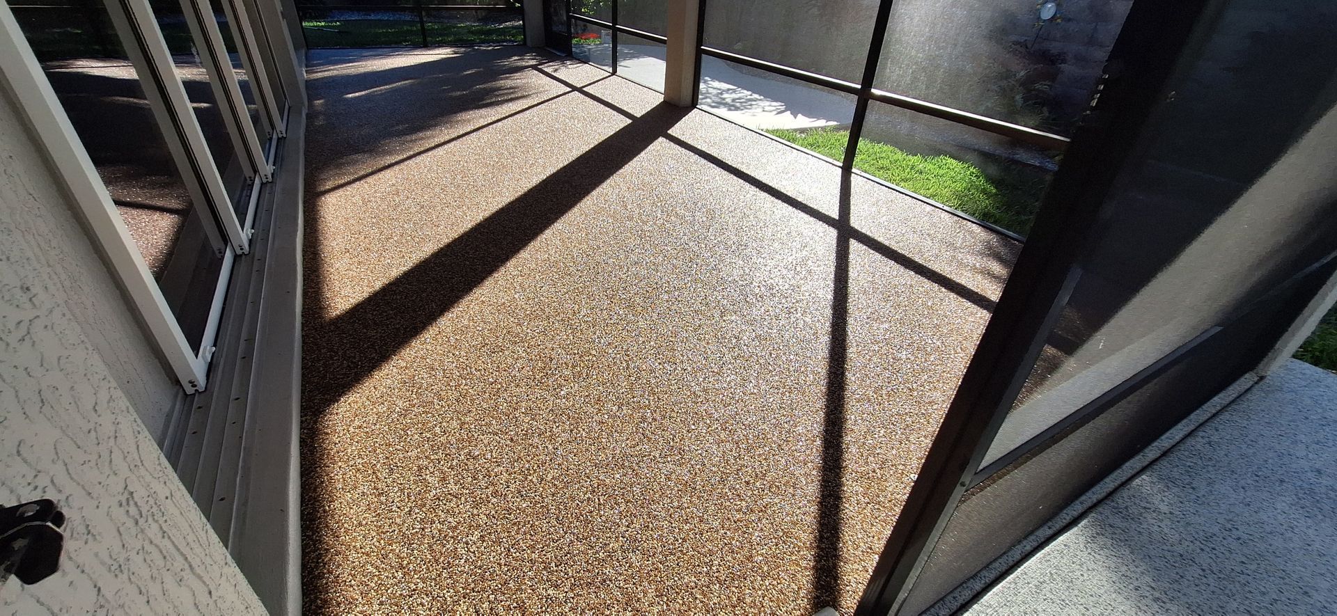 A patio with a screen door and a shadow on the ground