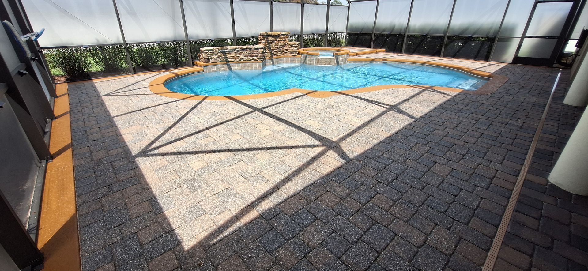 A large swimming pool is surrounded by a screened in area.