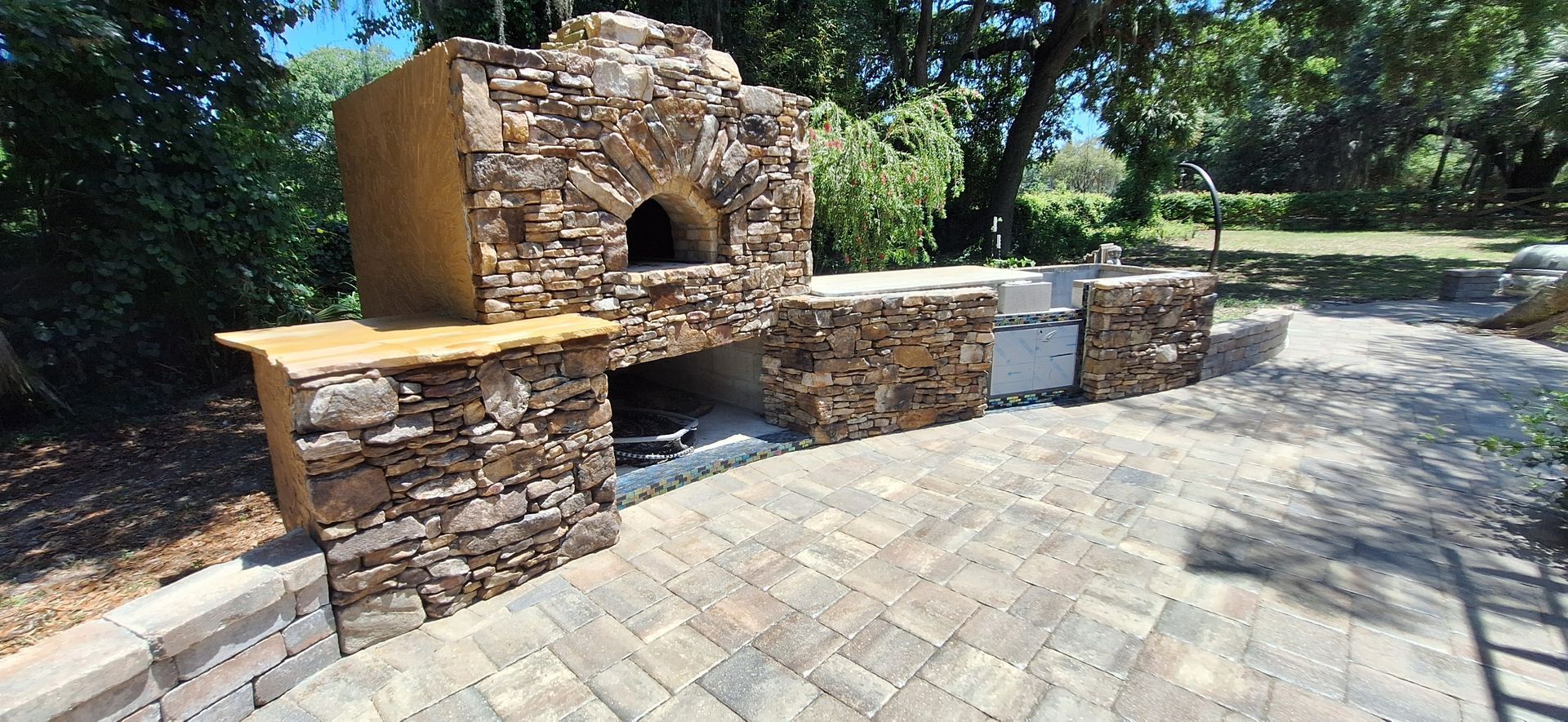 A stone oven is sitting on top of a brick patio.