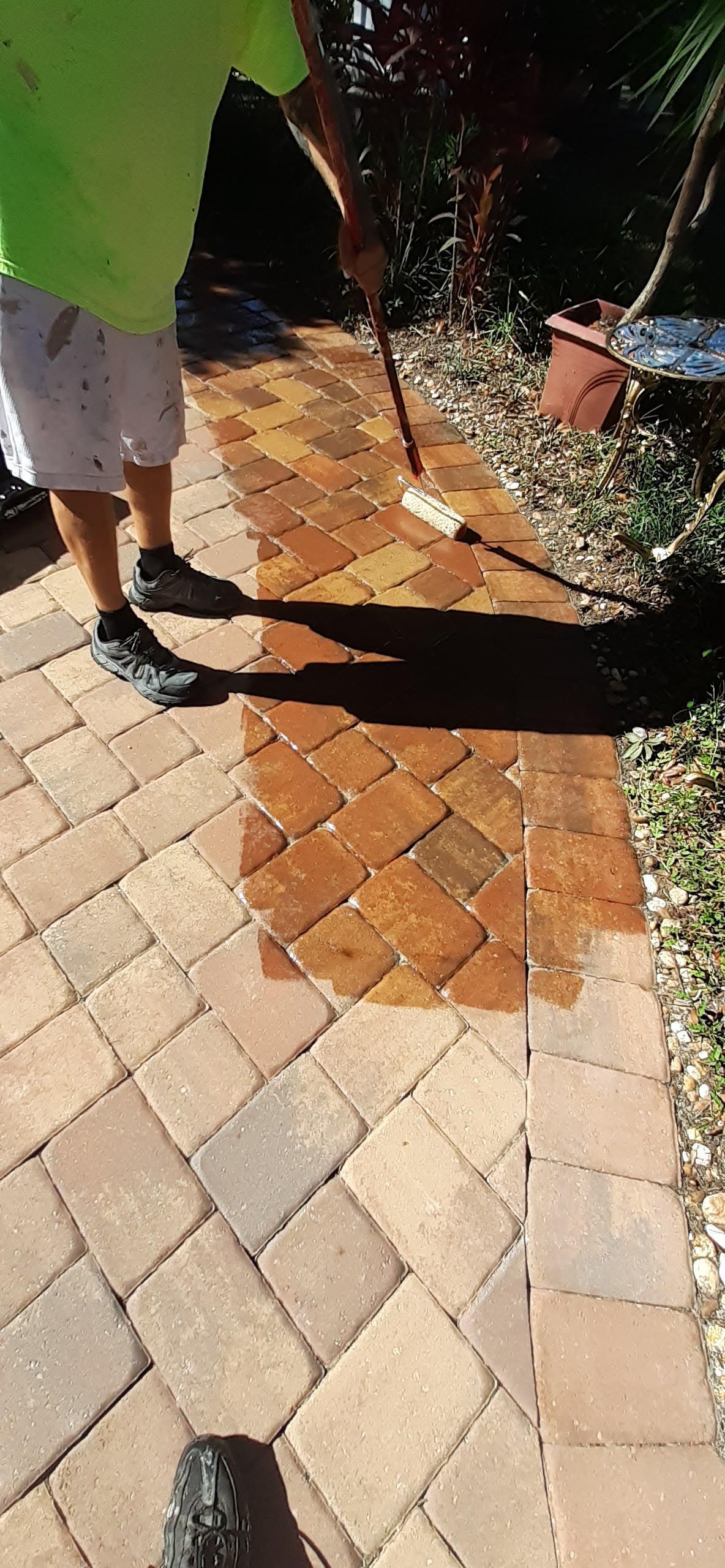 A person is cleaning a brick walkway with a broom.