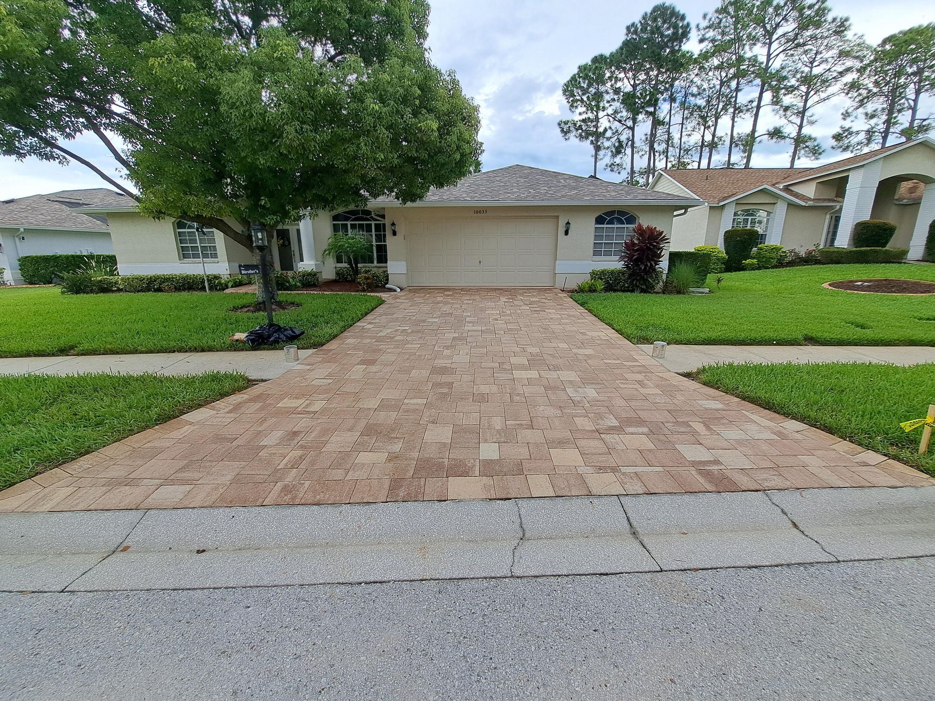 There is a brick driveway leading to a house.