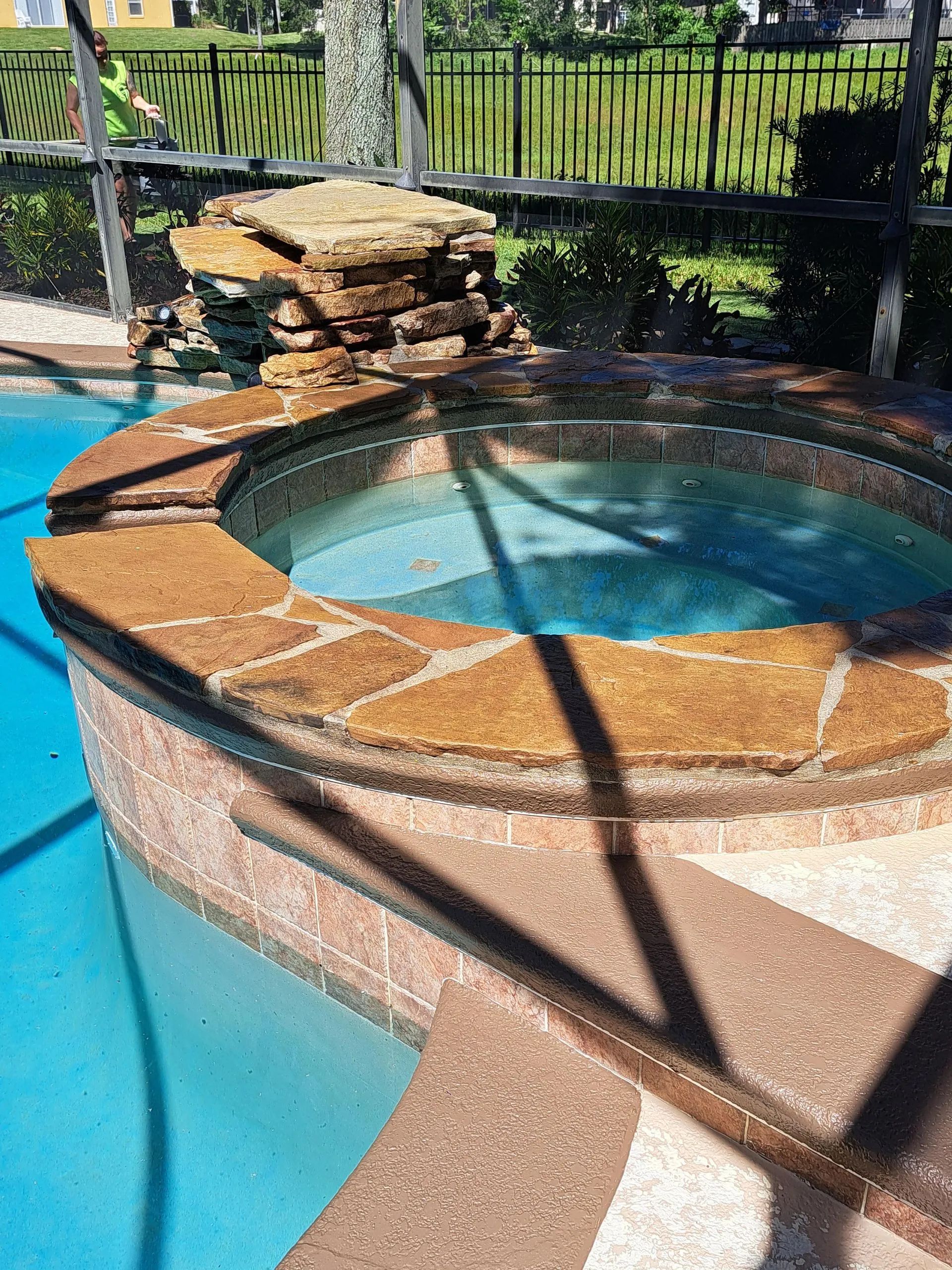 A swimming pool with a hot tub in the middle of it.
