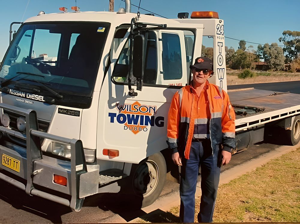 Man in Orange Safety Vest Stands Next to His Tow Truck — Tow in Dubbo, NSW