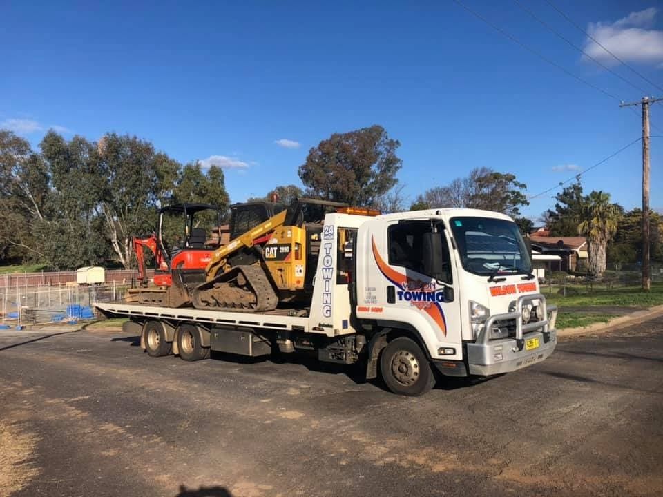 Tow Truck Carrying a Yellow Bulldozer and a Red Excavator on Its Flatbed