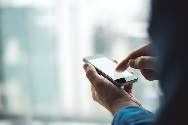 a man is using a smart phone in front of a window .