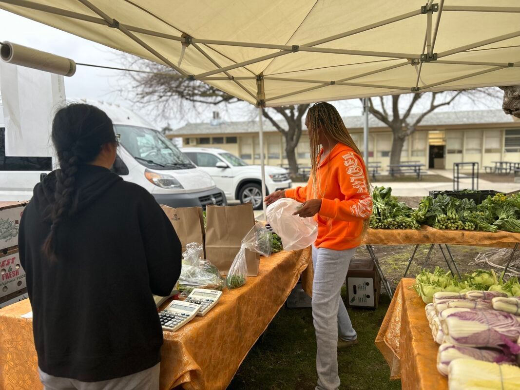 Chelsi Allen, a mother with children in a Fresno private school, buys farm-grown produce at a Fresno Unified farmers market. Allen saw the market while picking up her daughter from a basketball game at Fort Miller Middle School on February 5, 2024.