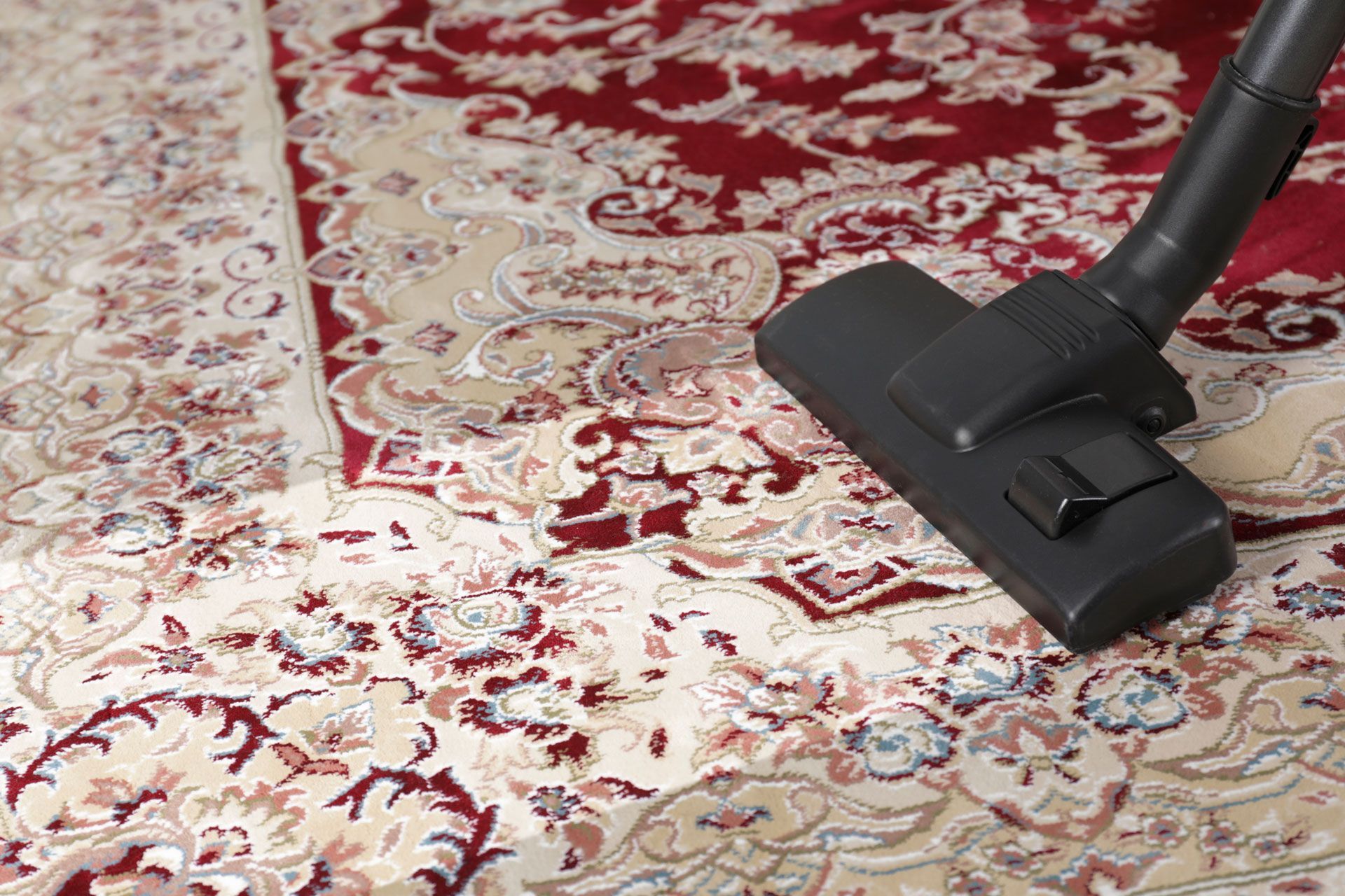 Vacuum cleaner head on a red and cream patterned carpet