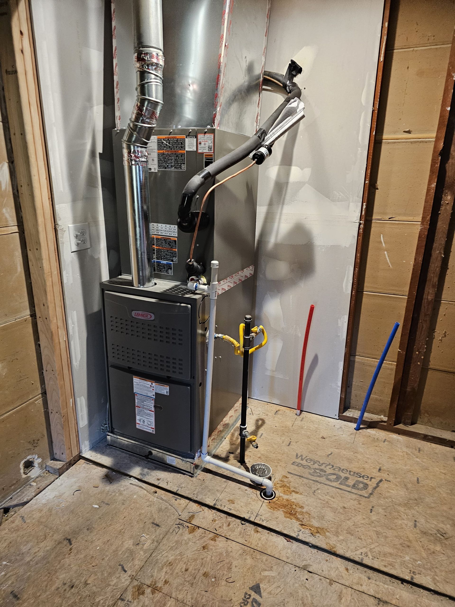 Furnace installed in unfinished room. Silver metal and black pipes. Gas line and flue visible.