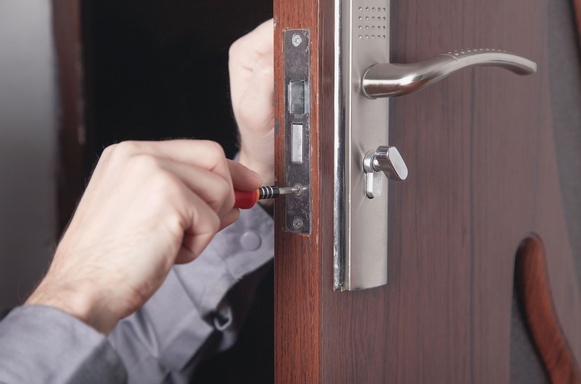 A man is fixing a door with a screwdriver.