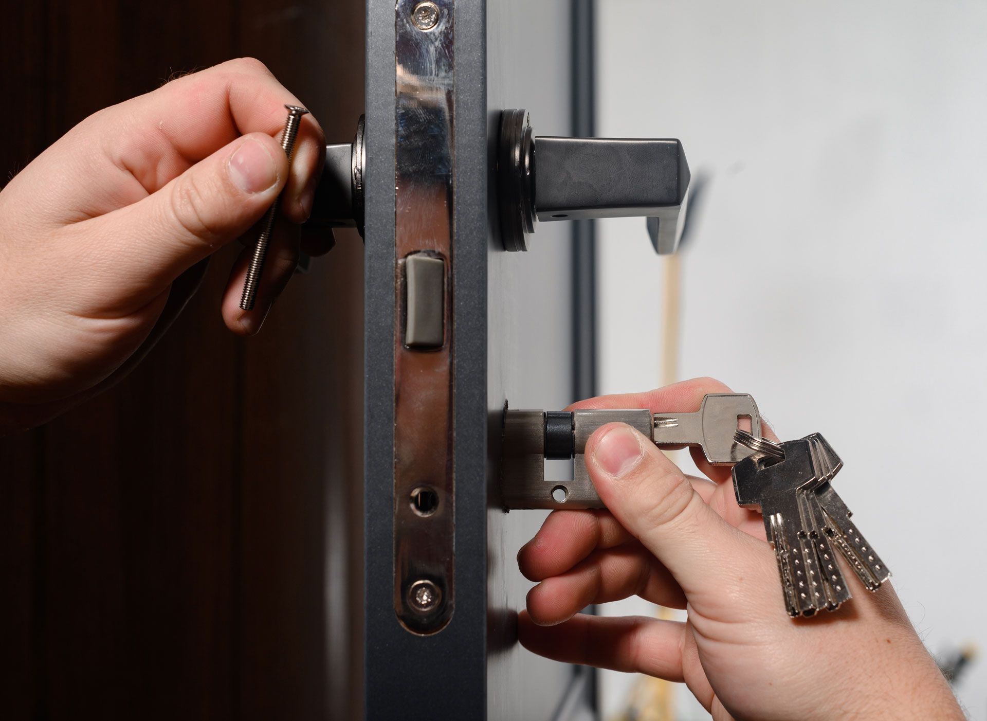 A person is fixing a door lock with keys.