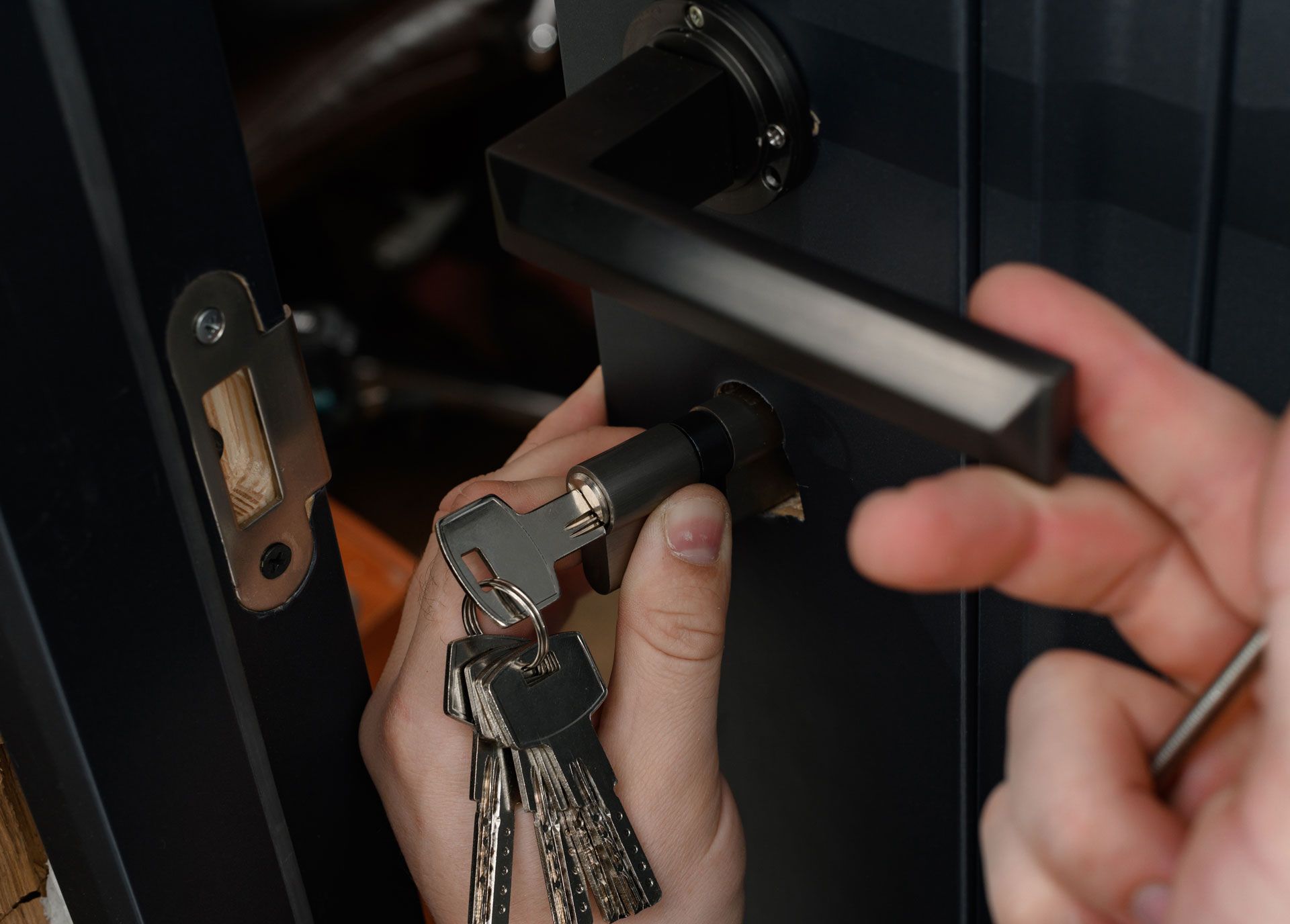 A person is holding a bunch of keys and trying to open a door.