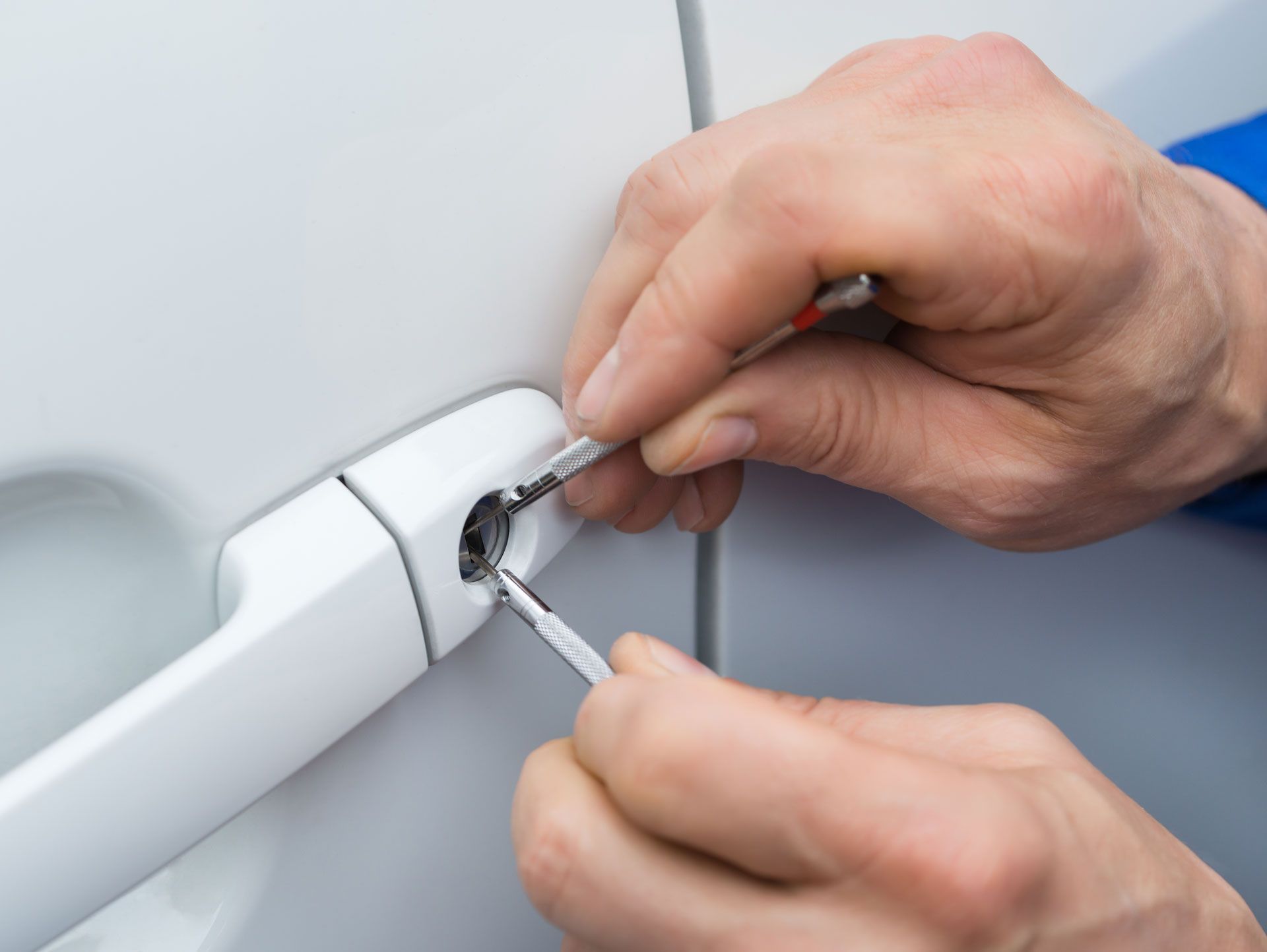 A person is using a wrench to open a car door.