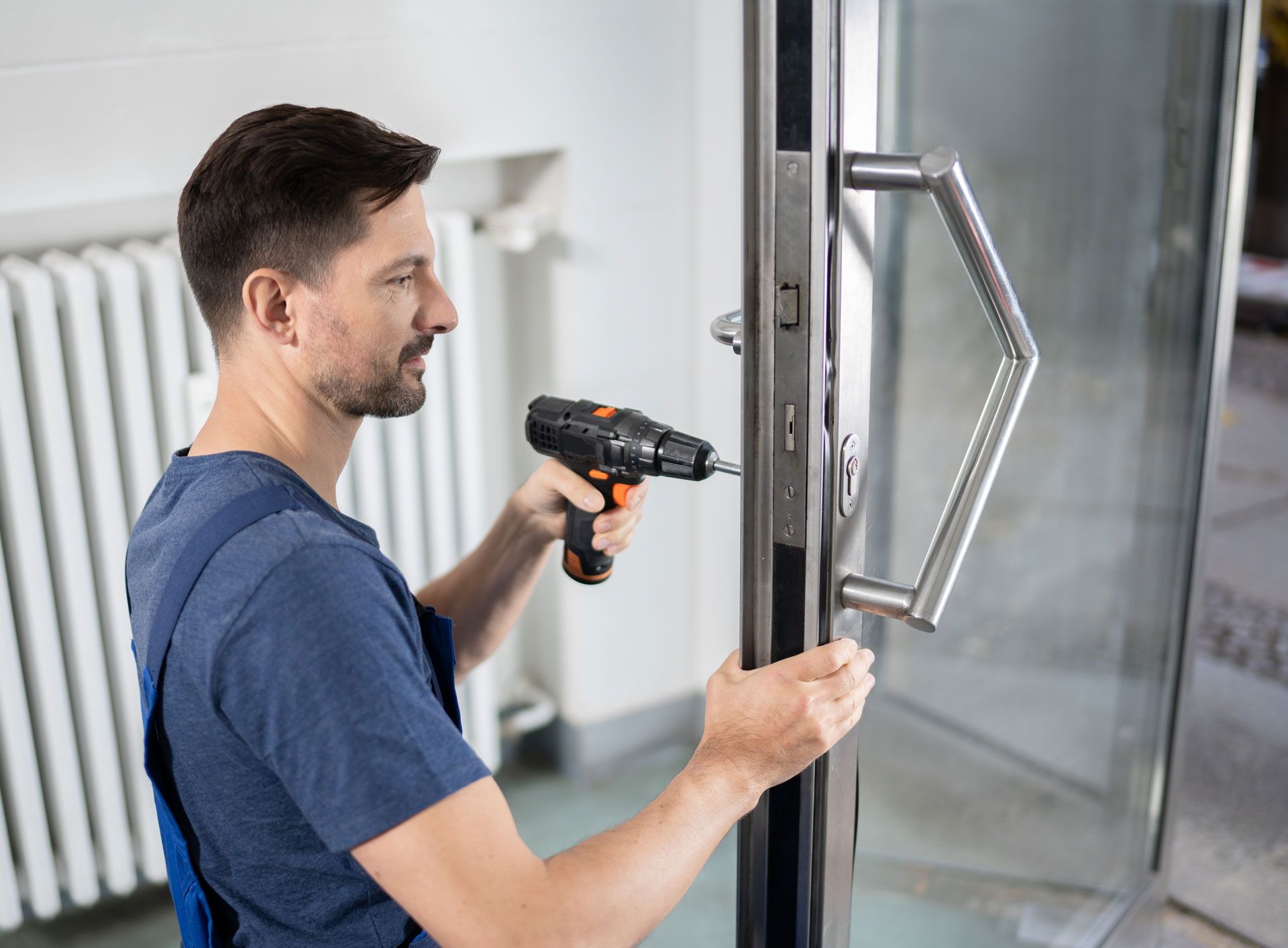 A man is fixing a door with a drill.