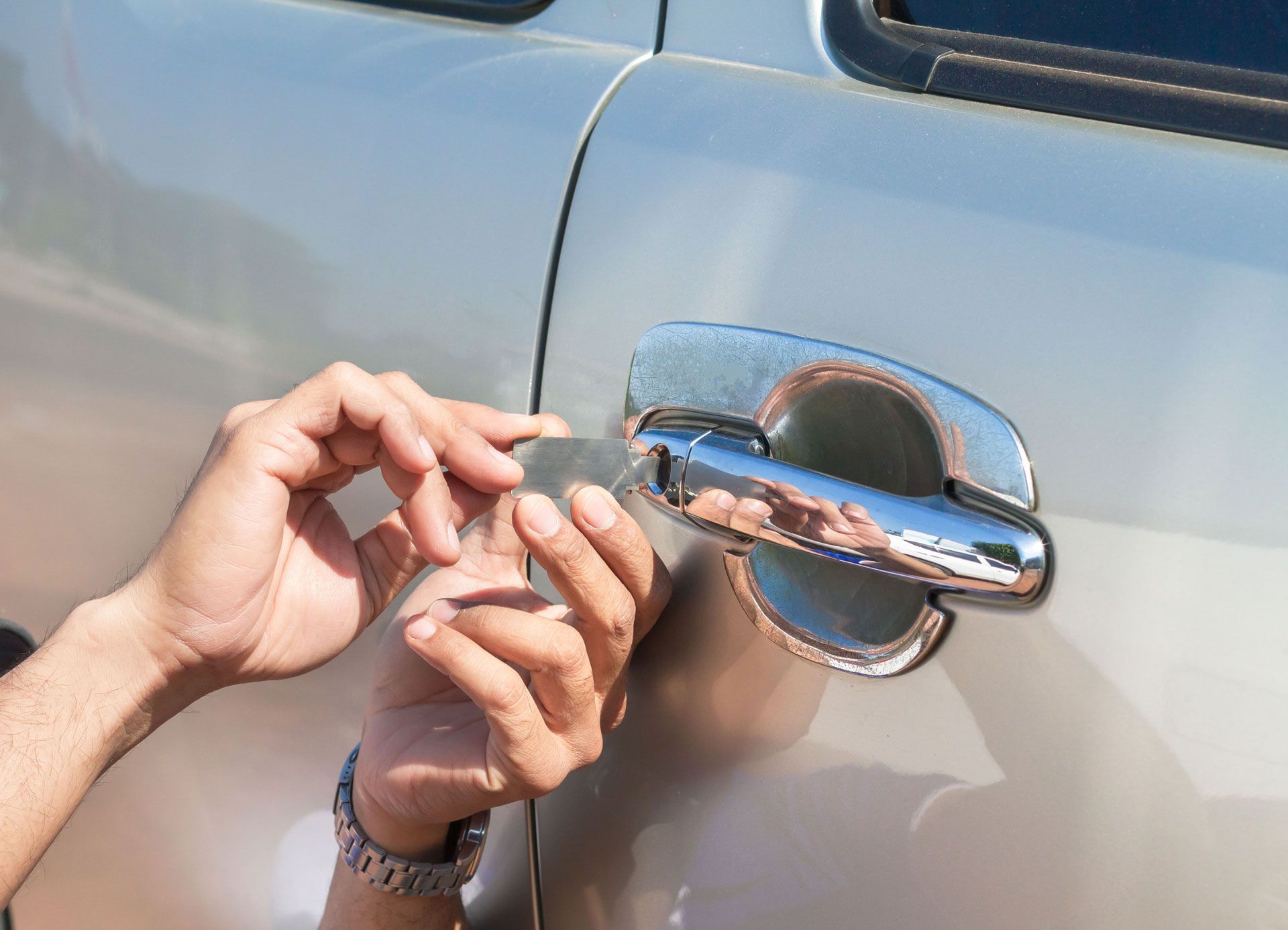 A person is trying to open a car door with a key.