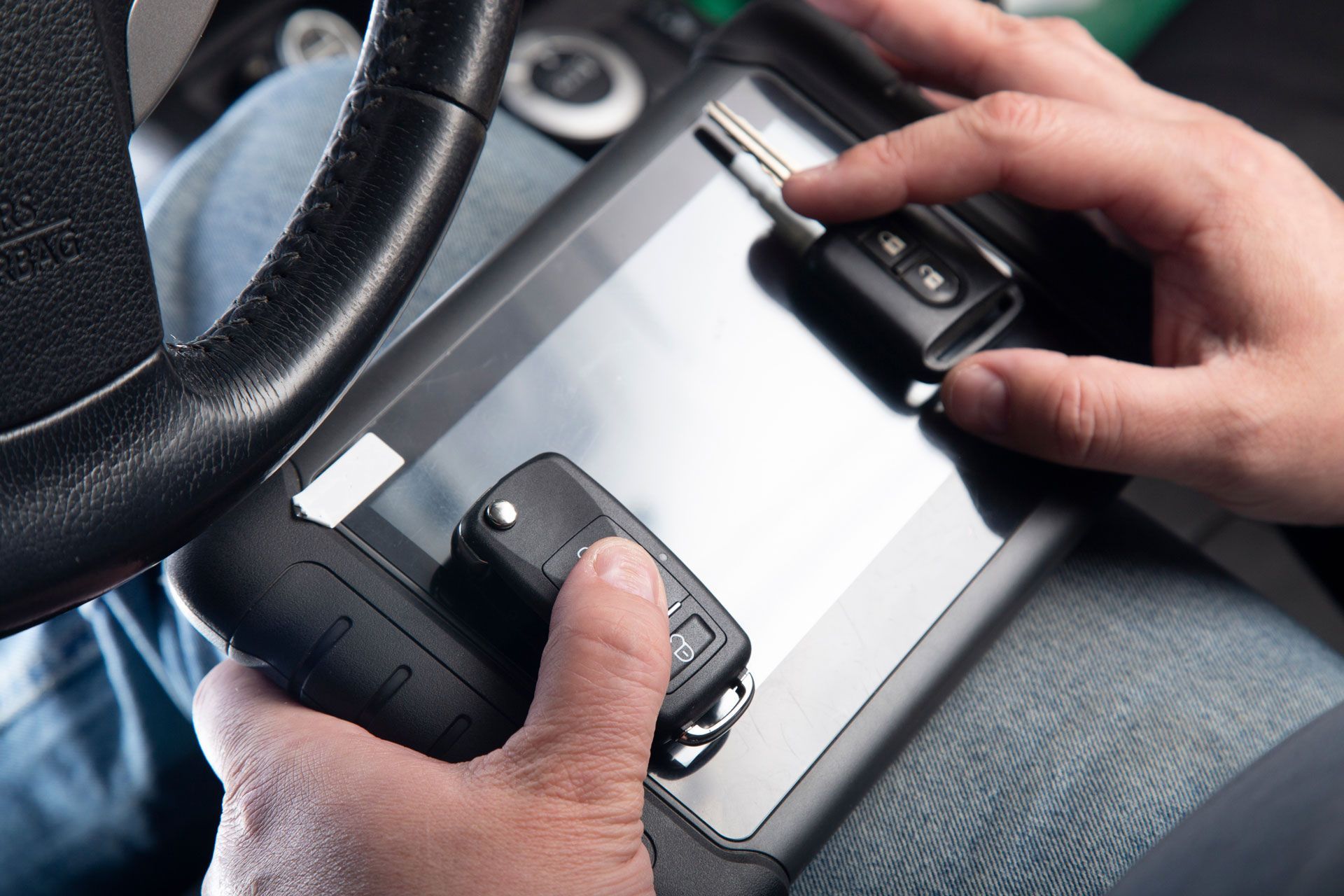 A person is holding a car key and pressing a button on a device.