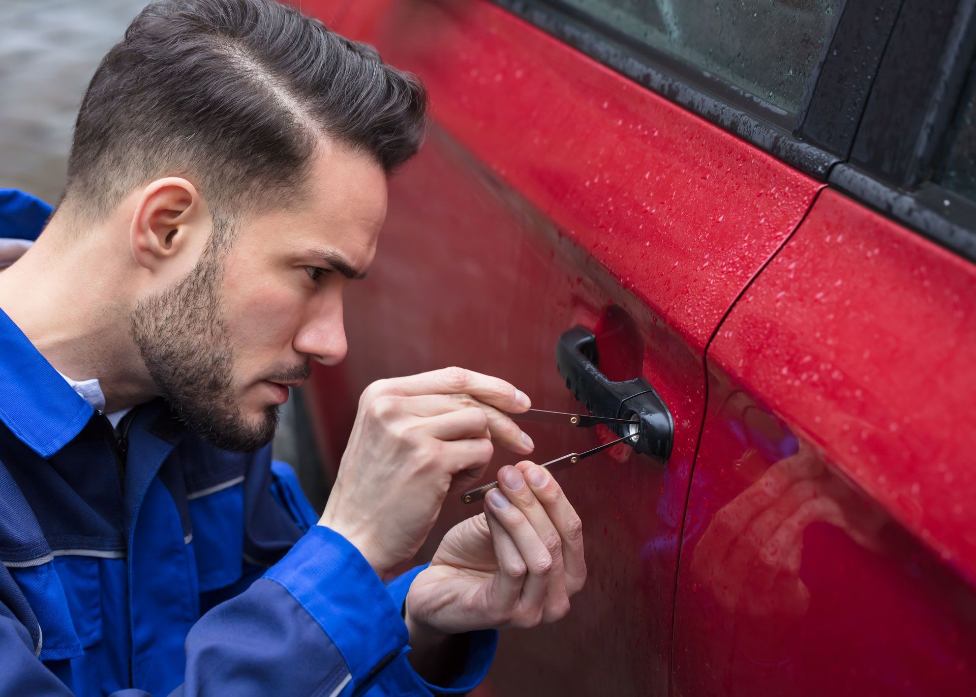 A man is trying to open the door of a red car.