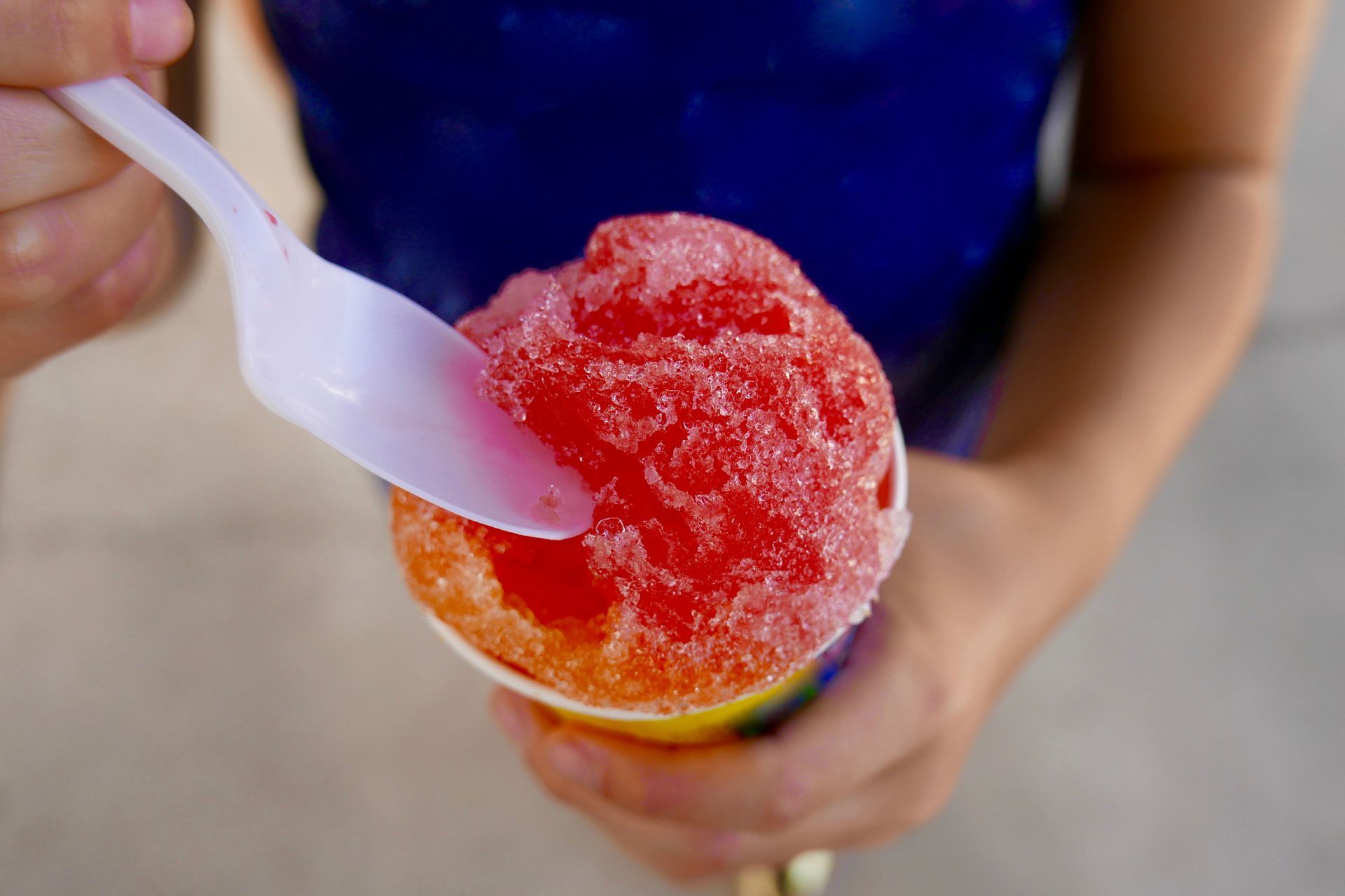 A person is eating a shaved ice with a spoon.