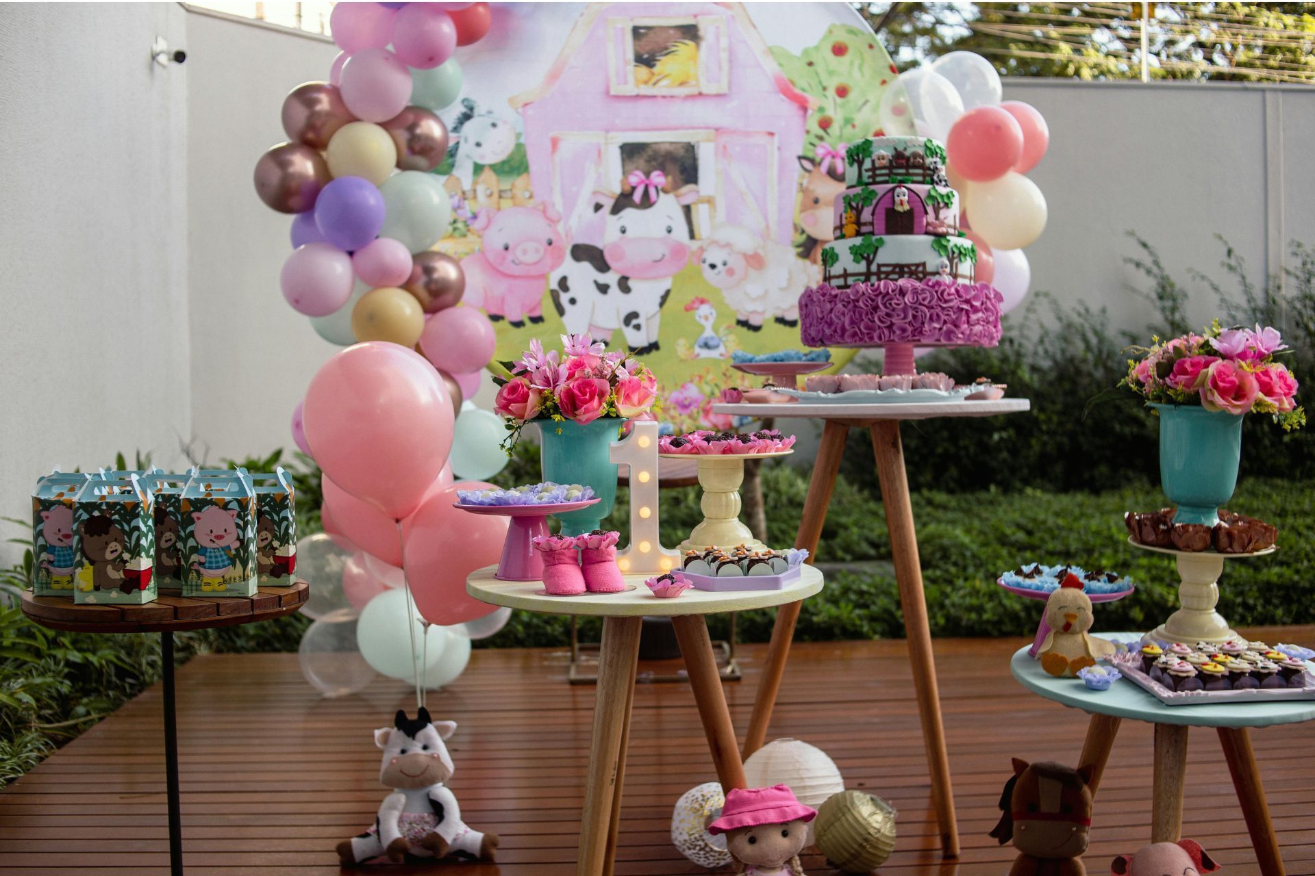 A table decorated with balloons , flowers , and cakes for a birthday party.