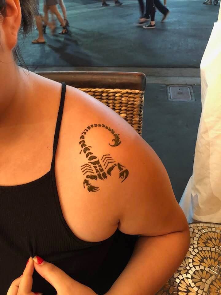 A woman has a tattoo of a scorpion on her shoulder