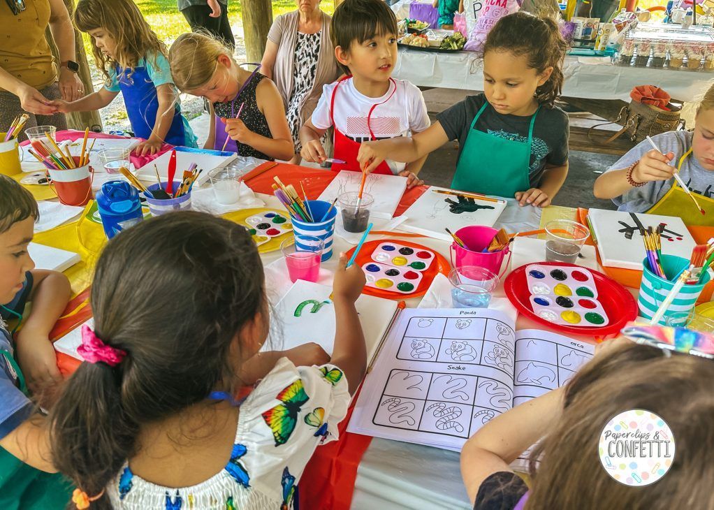 A group of children are sitting at a table painting.