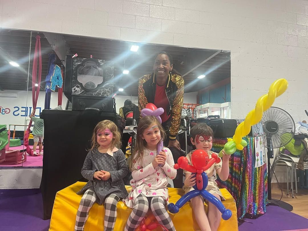 A group of children are sitting on a couch with balloons on their faces.