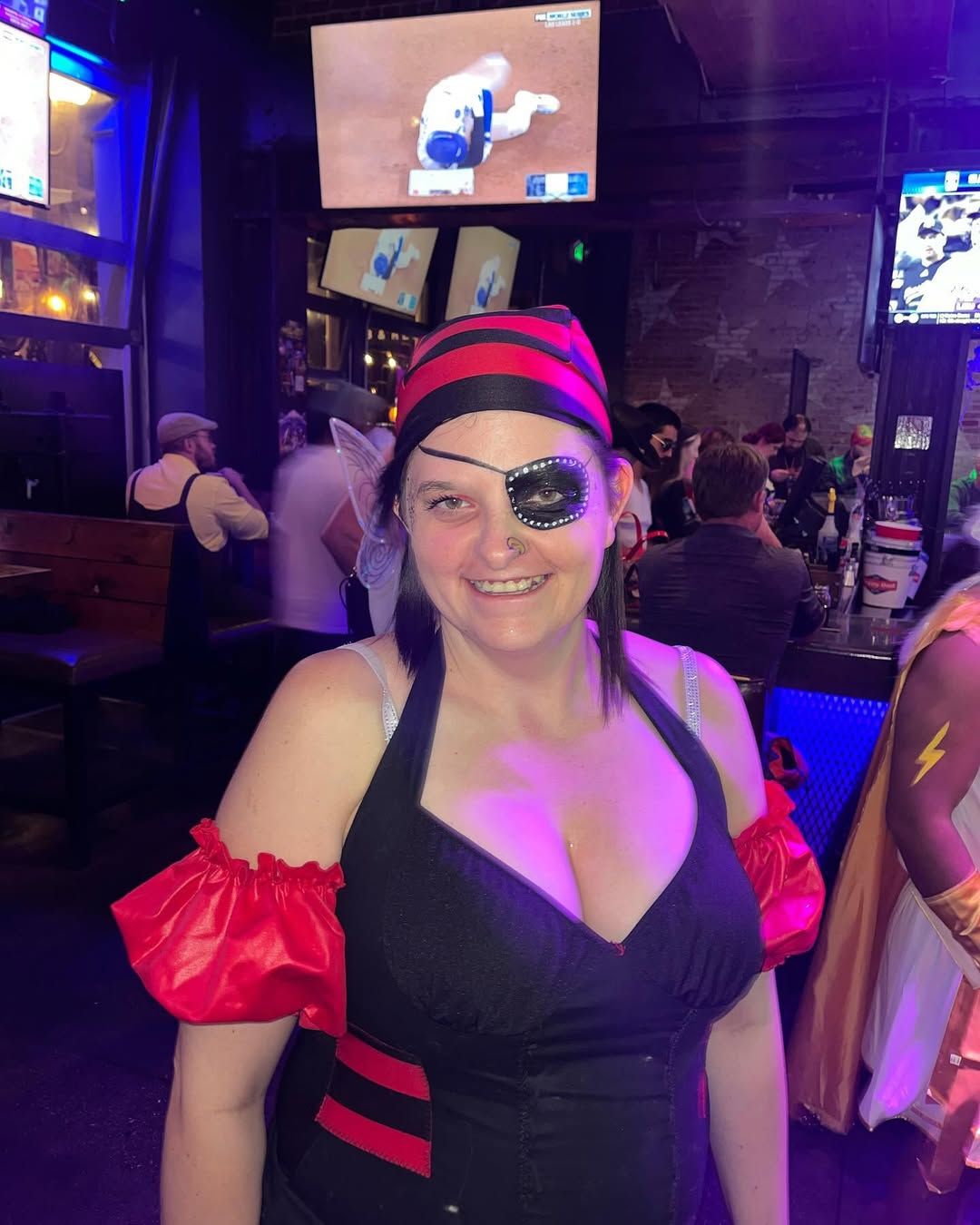A woman in a pirate costume is smiling in a bar