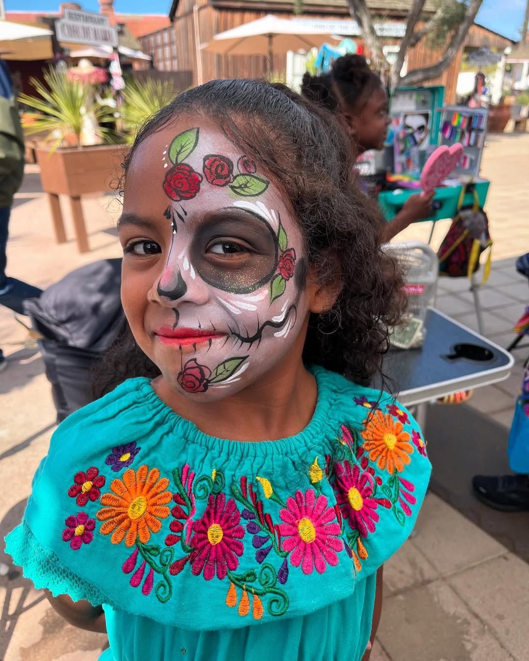 A little girl with a skull painted on her face.
