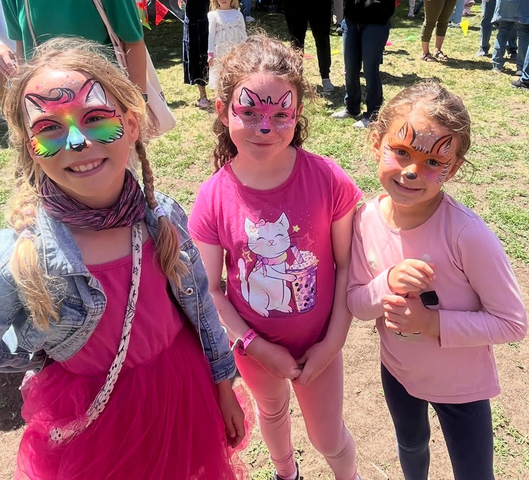 Three young girls with face paint on their faces are posing for a picture.