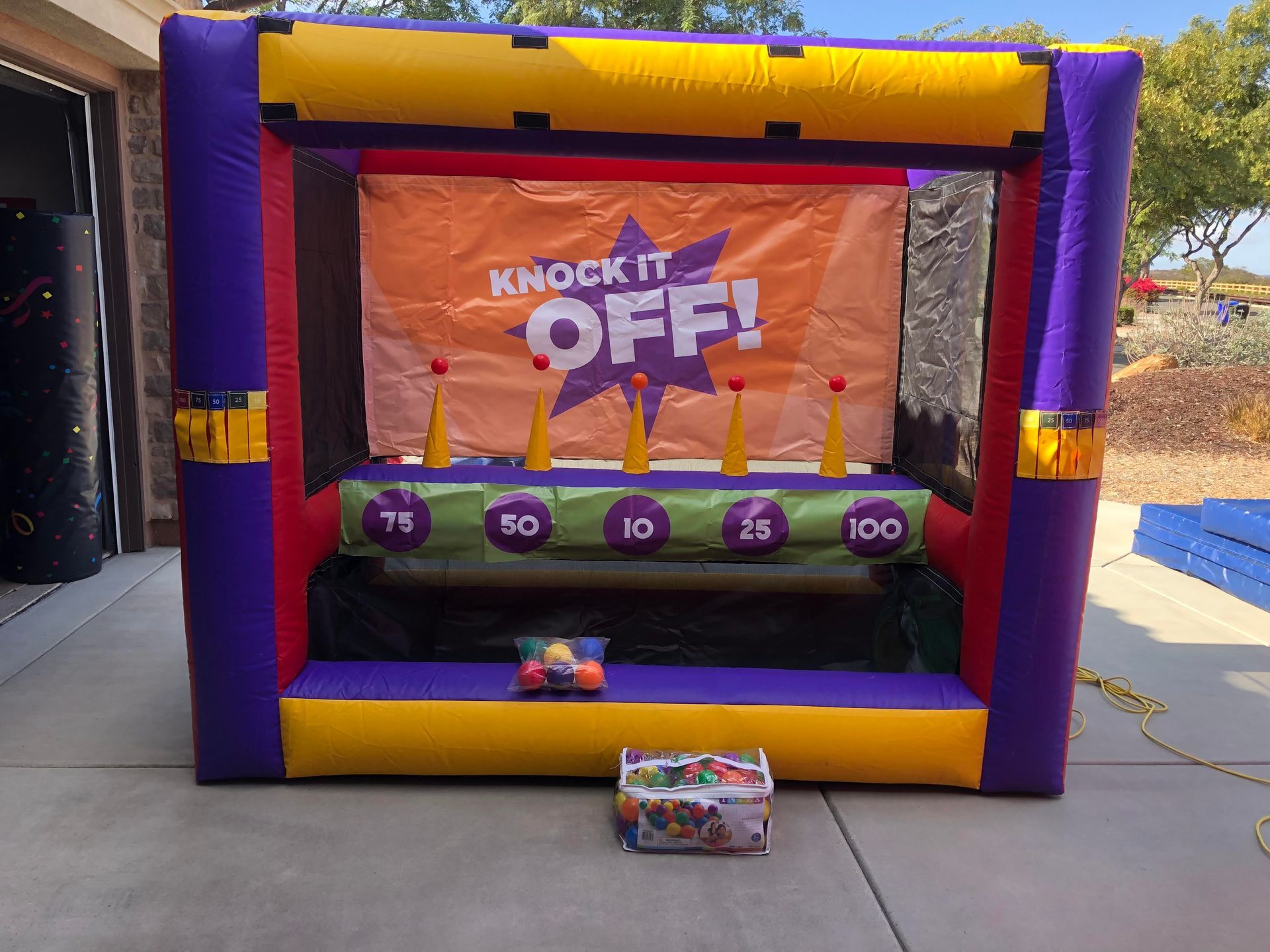 A knock it off inflatable game is sitting in a driveway.