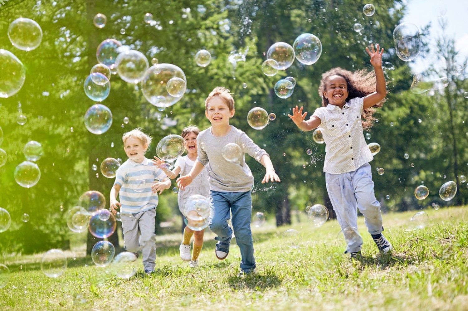 A group of children are playing with soap bubbles in a park.