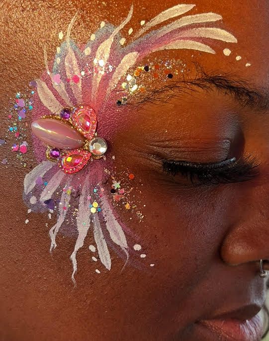 A close up of a woman 's face with a flower painted on it.