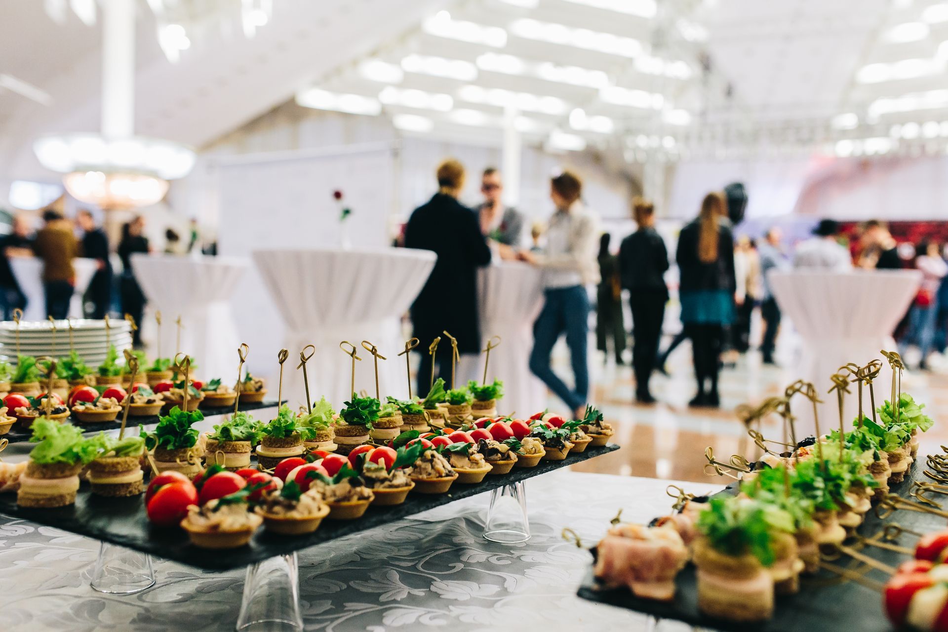 A buffet table filled with lots of food and people standing around tables.