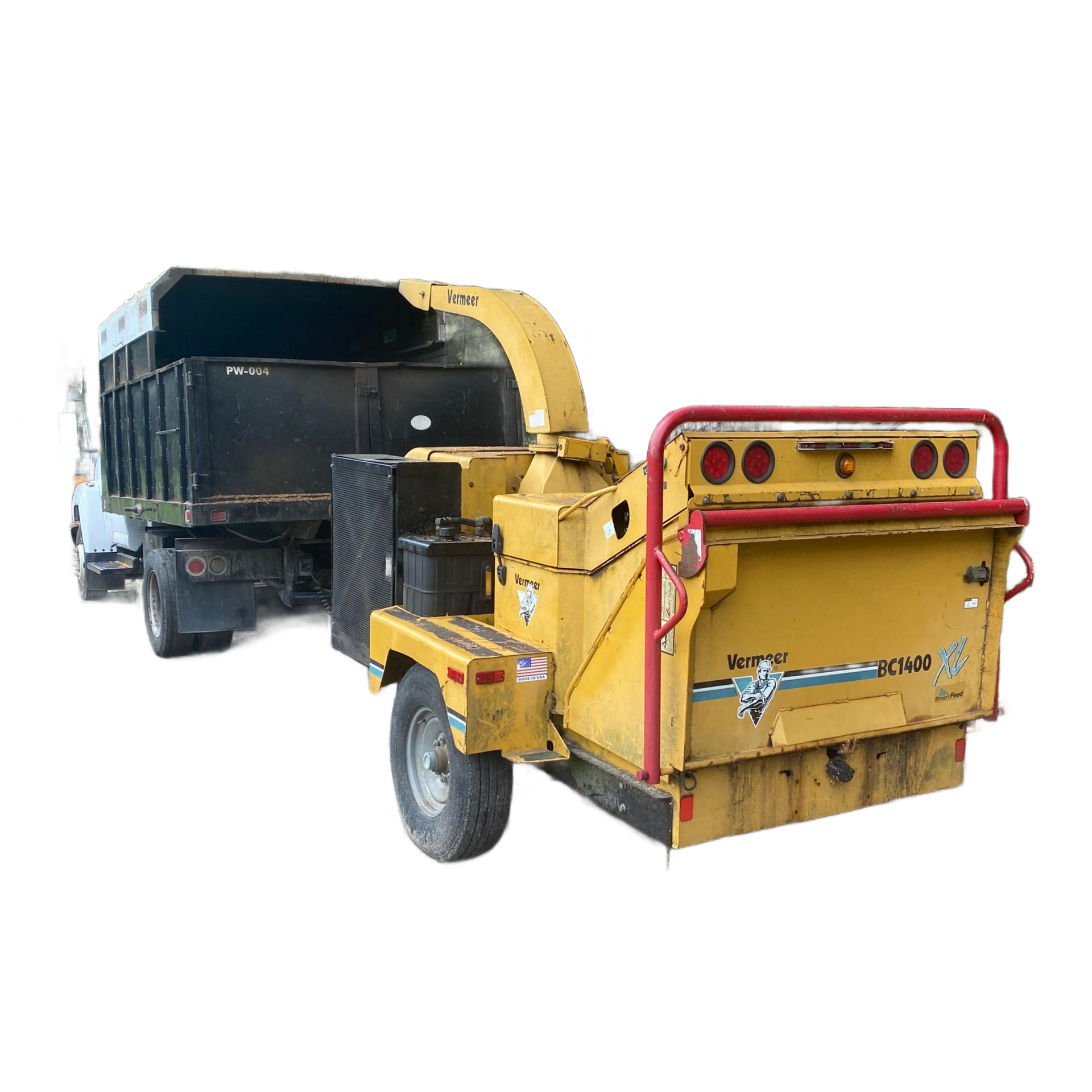 Yellow wood chipper connected to a truck, used for processing tree debris in a wooded area.