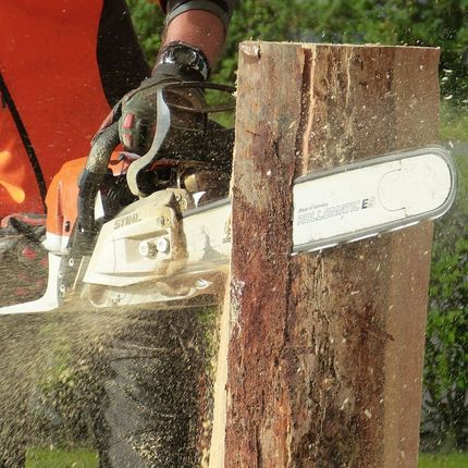 A person is using a chainsaw to cut a piece of wood