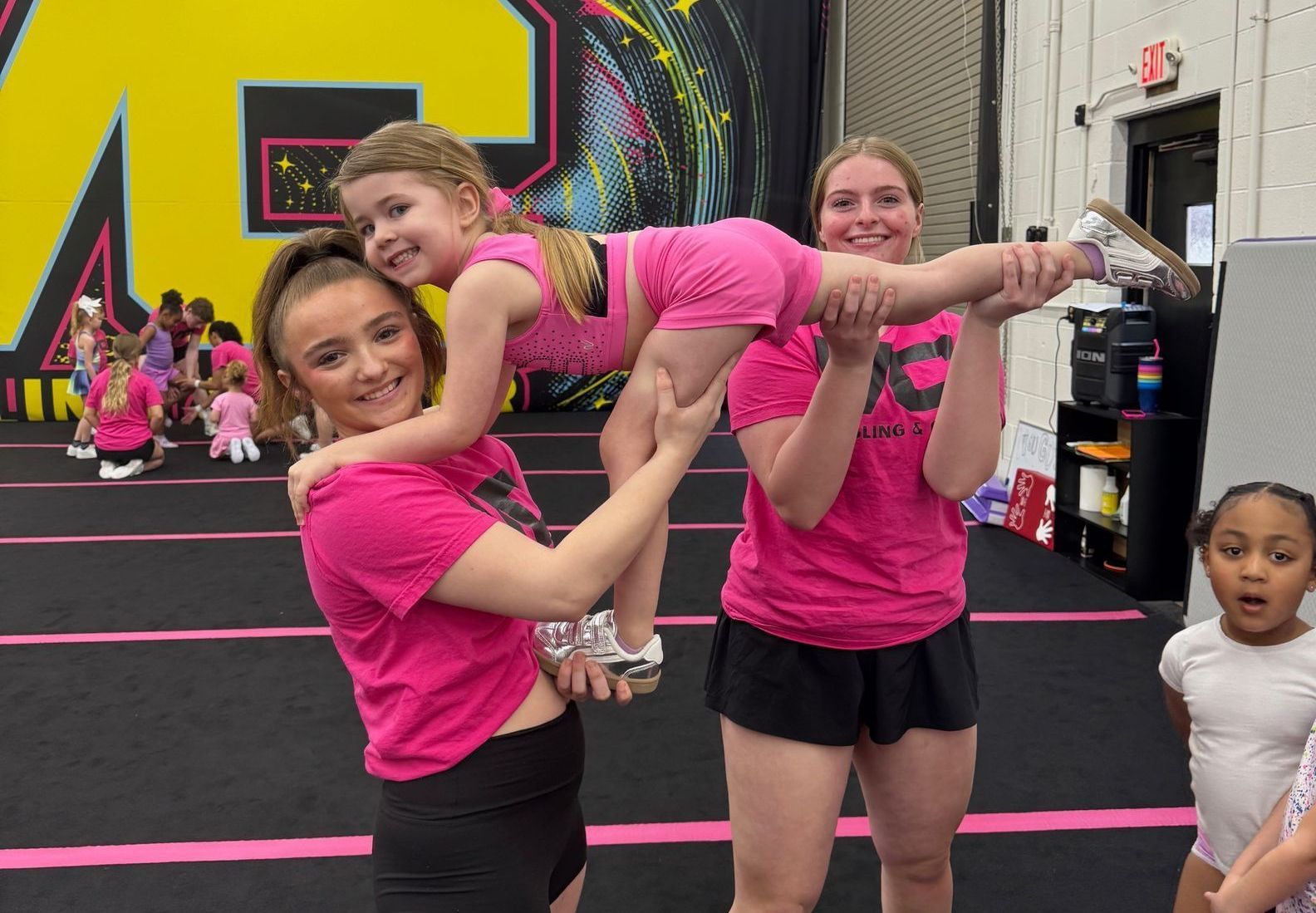 A woman is holding a little girl in her arms in a gym.