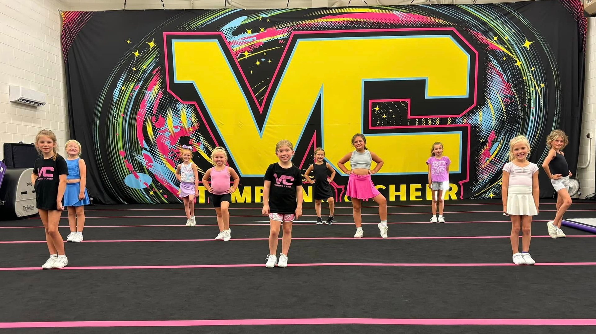 A group of young girls are standing in front of a large yellow sign.