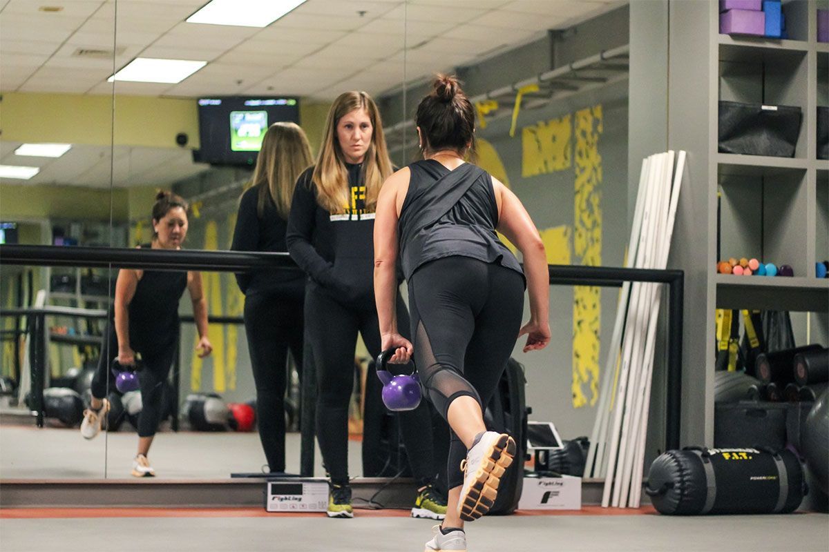 A woman is running with a kettlebell in a gym.