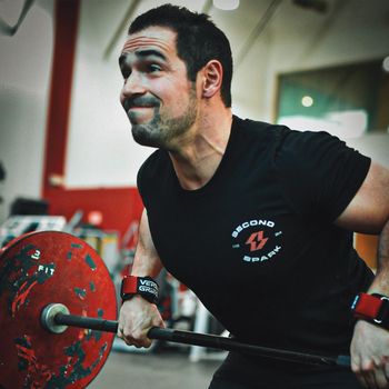 a man wearing a black shirt that says second spark is lifting a barbell