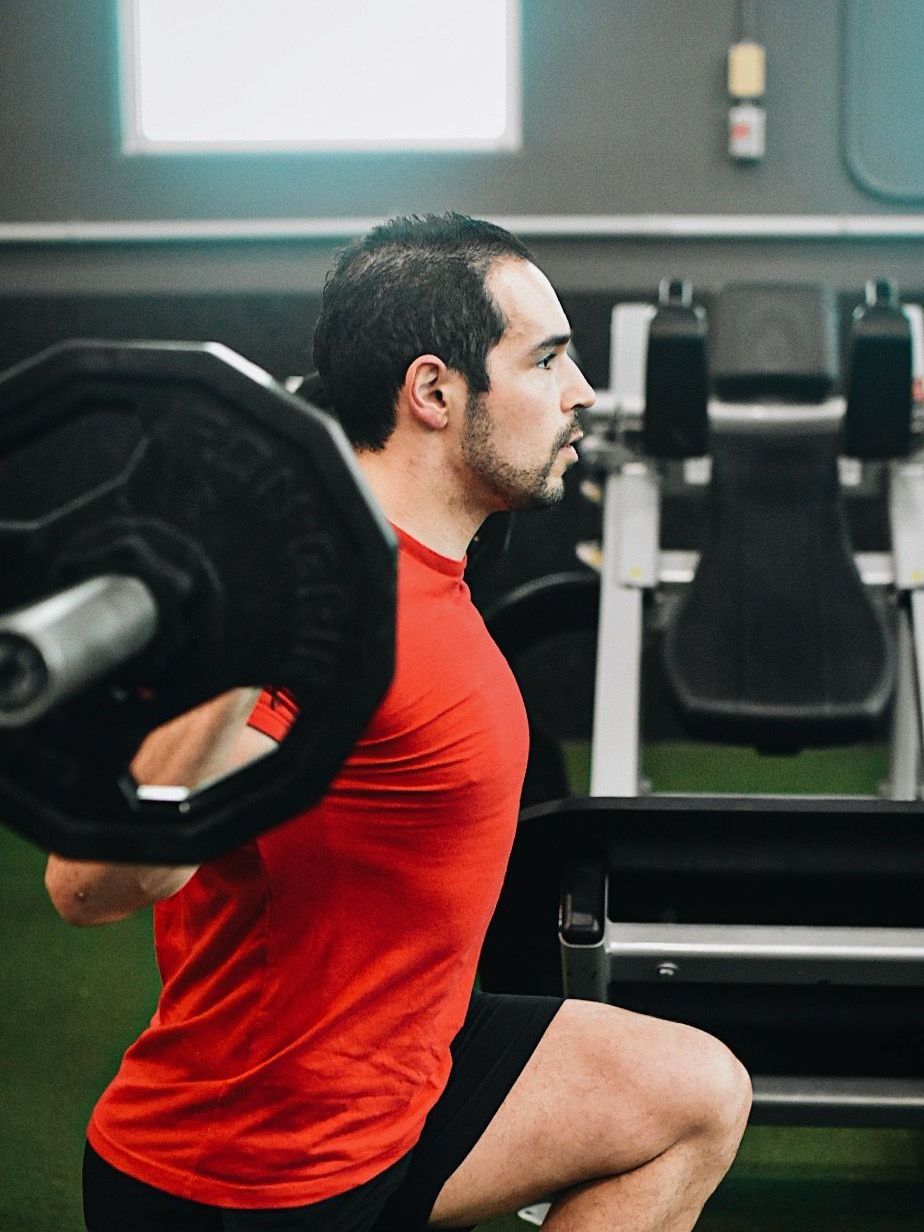 a man is squatting with a barbell on his shoulders in a gym .