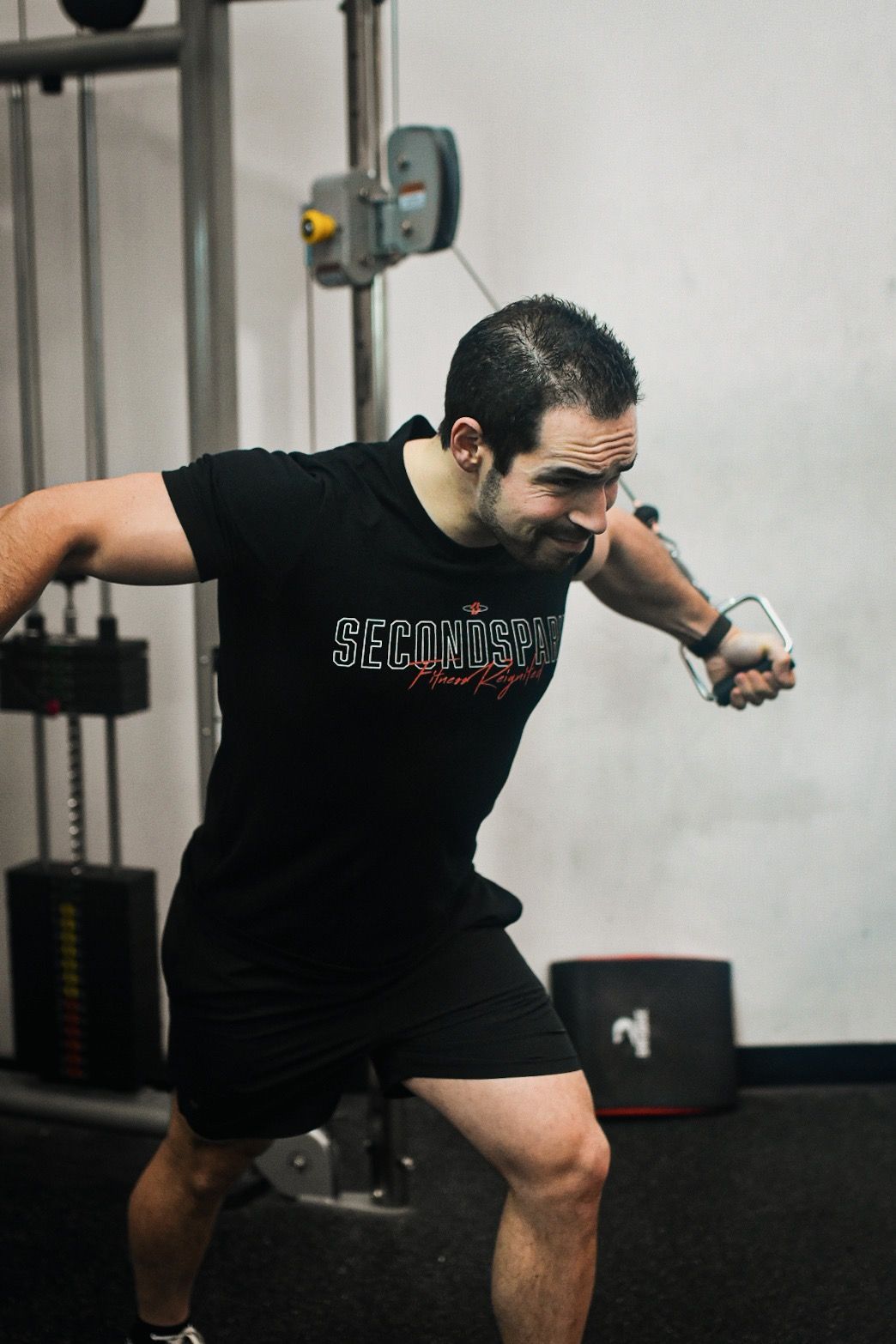 A man in a black shirt is using a machine in a gym.