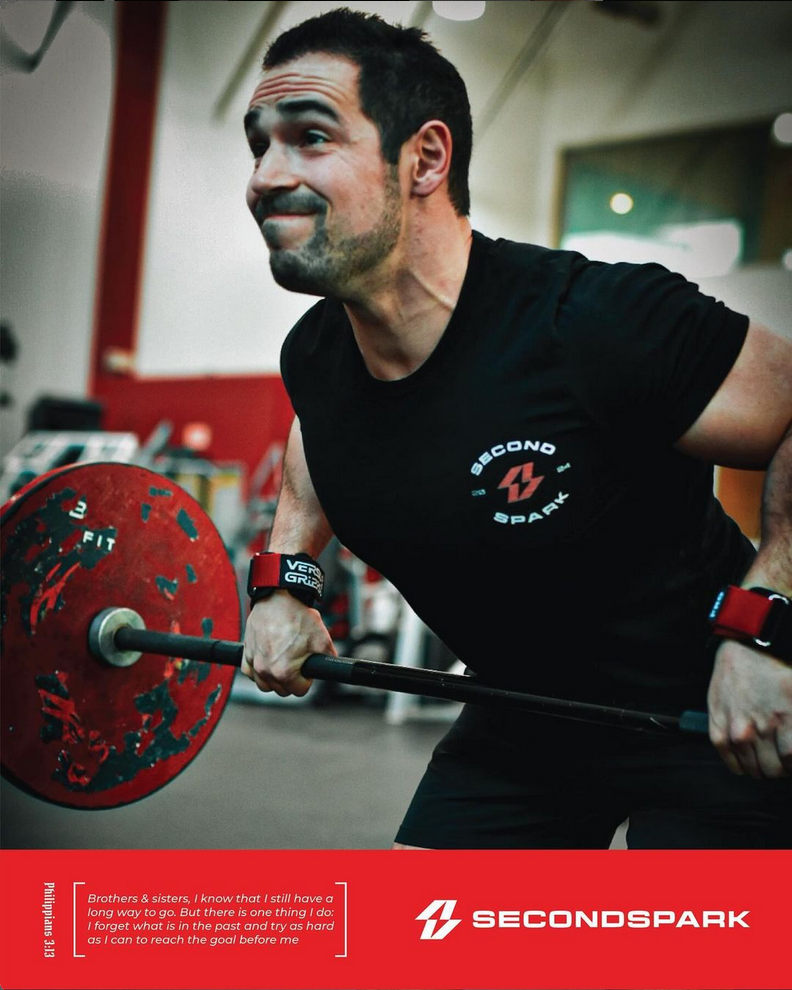 A man in a black shirt is lifting a barbell in a gym.