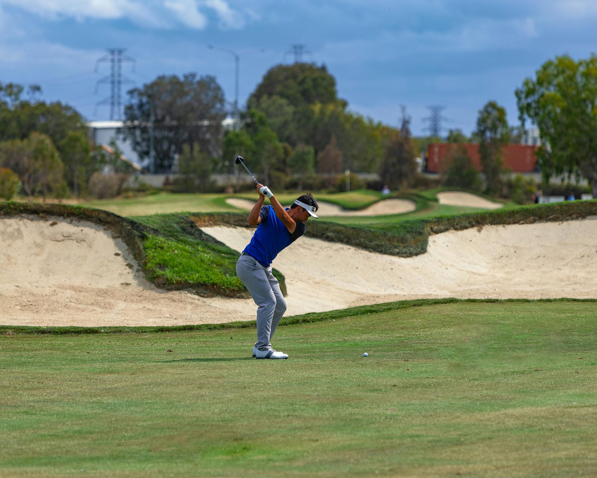 Golfer swinging club on green course with Credit Suisse signage behind him.