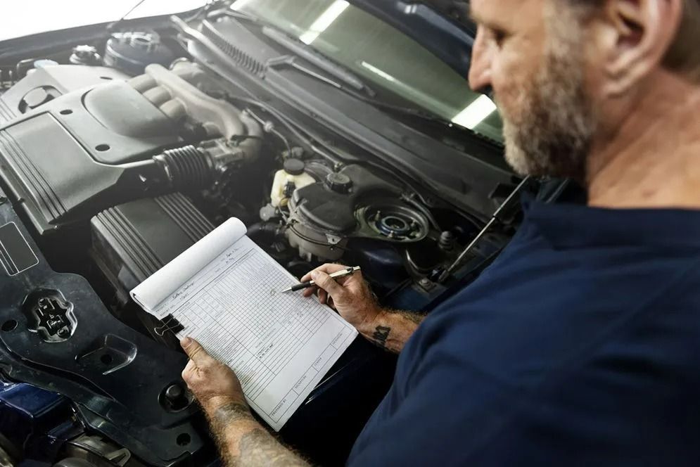 Mechanic Inspecting a Car Engine and Writing Notes — Fischer Automotive in Svensson Heights, QLD