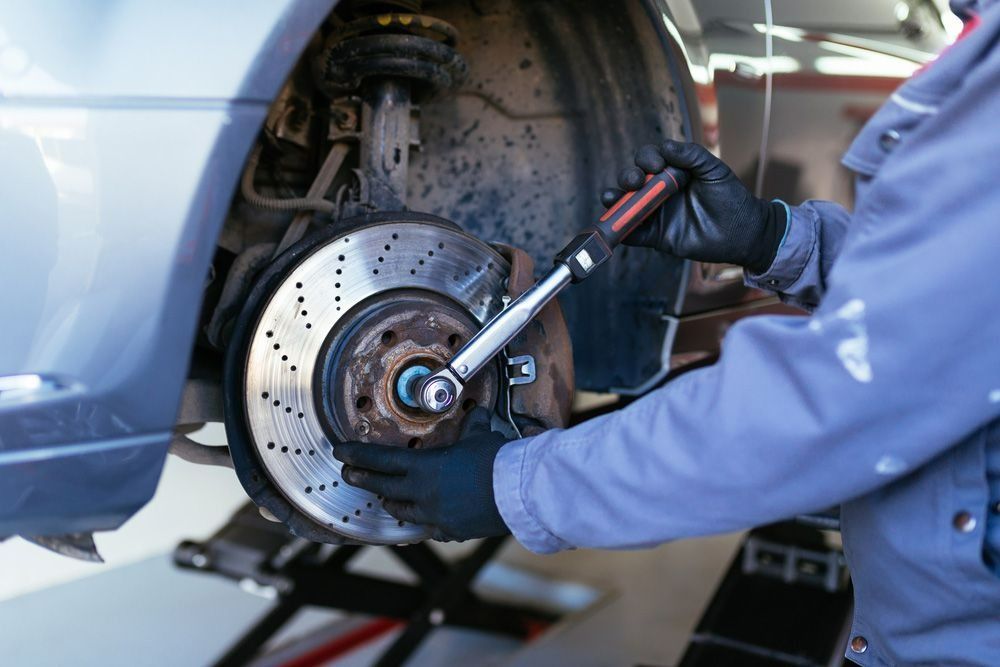 Mechanic Using a Wrench to Remove a Car Wheel in a Garage — Fischer Automotive in Svensson Heights, QLD