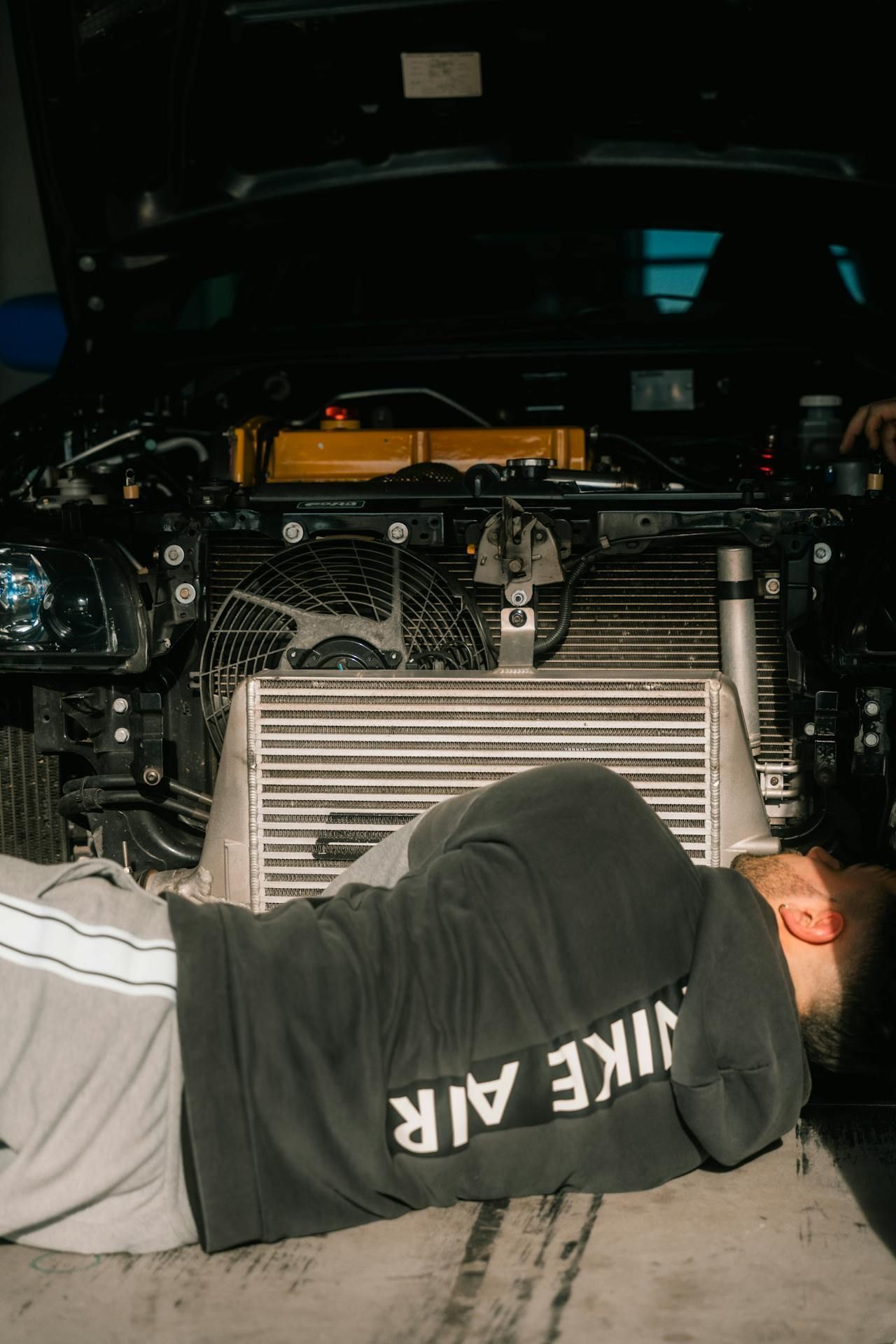 Mechanic Lying Under a Car Inspecting the Front Grille — Fischer Automotive in Svensson Heights, QLD