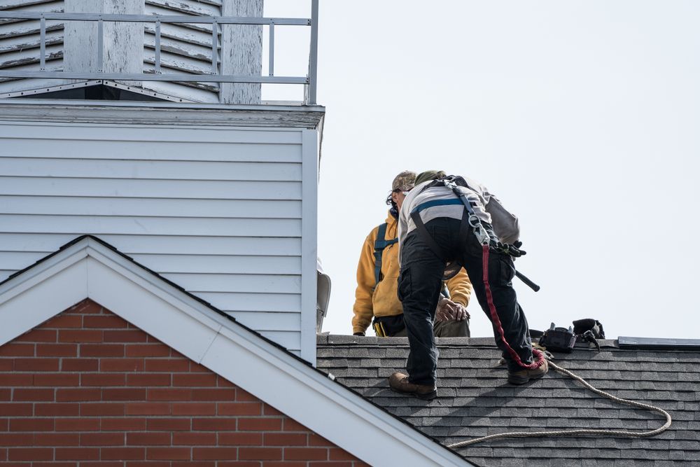 Two Men Are Working on the Roof of a Building — RJT Roofing In Bonner, ACT