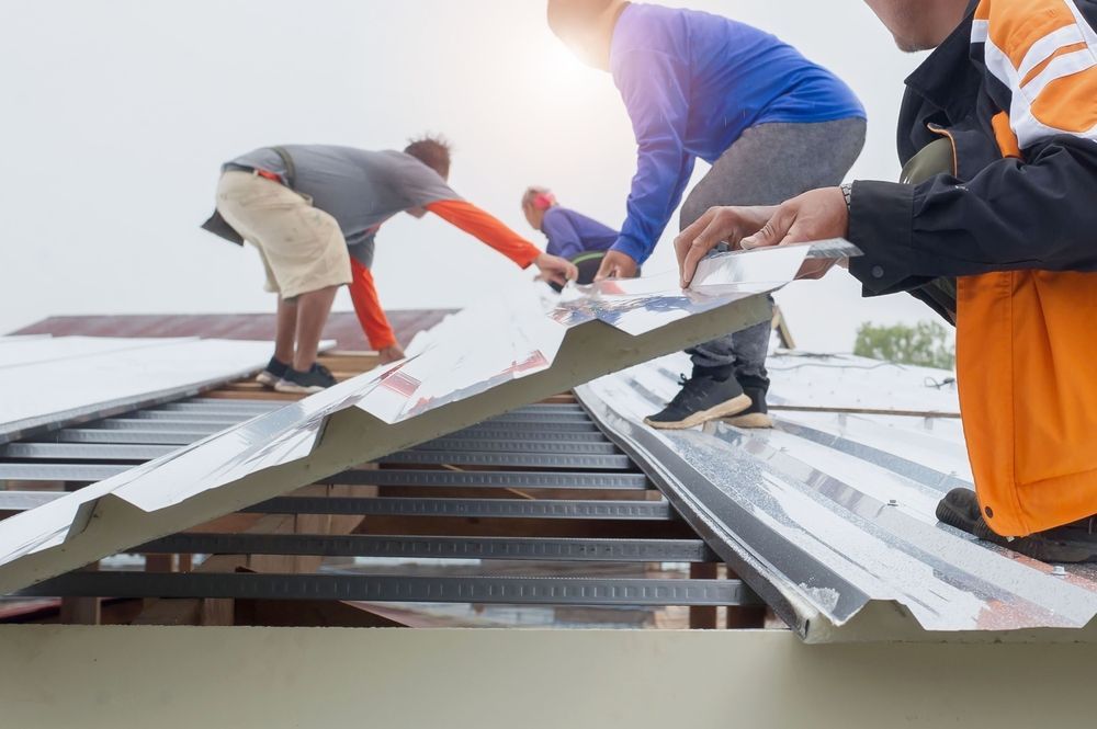 A Group of Men Are Working on a Metal Roof — RJT Roofing In Bonner, ACT