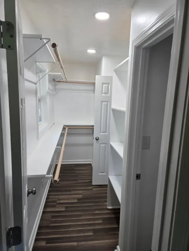 A walk in closet with lots of shelves and a door.