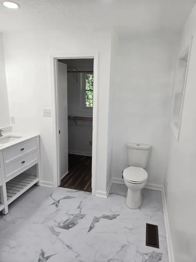 A bathroom with a toilet , sink and mirror.